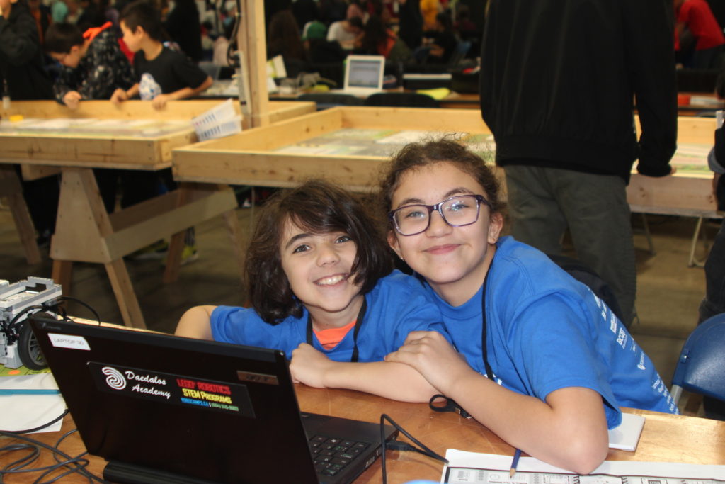 Two kids playing at a computer with robotics